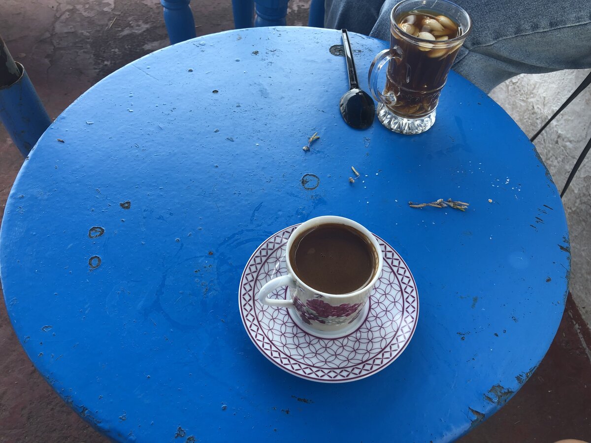 シディ・ブ・サイドのカフェで飲んだアラビックコーヒーとアーモンドティー（テーブルには前客の汚れが残ったまま）